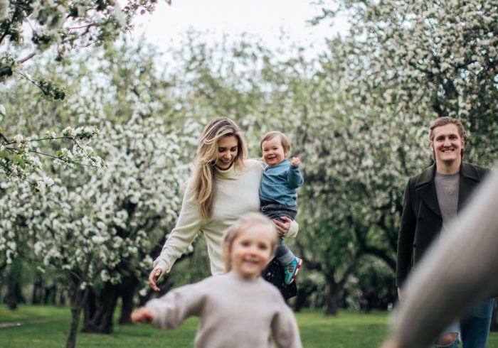 A joyful family enjoys a playful day outdoors amidst blossoming trees in spring.